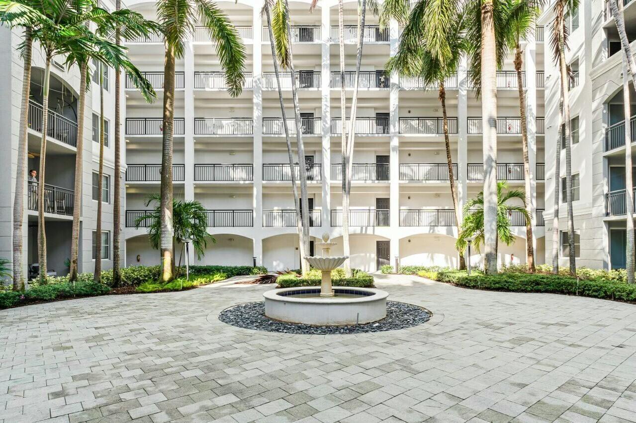 1690 Renaissance Commons Boulevard, Unit 1125 Boynton Beach, FL 33426 - Photo 24 of 37 a view of a building with a yard and palm trees