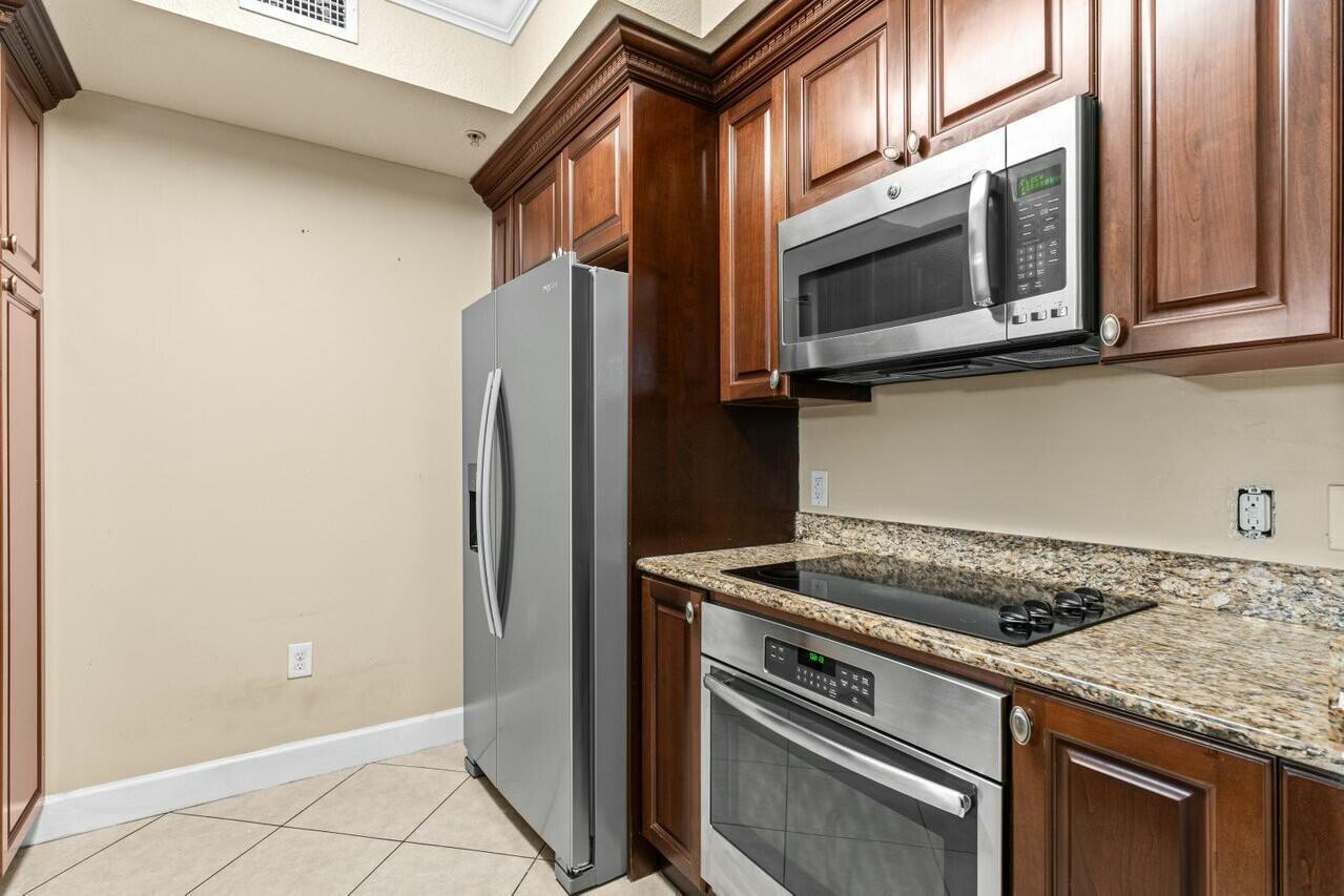 1690 Renaissance Commons Boulevard, Unit 1125 Boynton Beach, FL 33426 - Photo 5 of 37 a kitchen with stainless steel appliances granite countertop a stove microwave and refrigerator