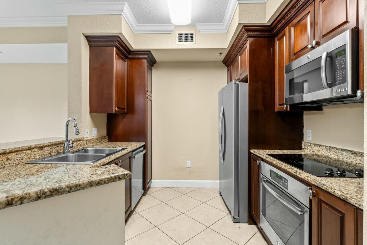 1690 Renaissance Commons Boulevard, Unit 1125 Boynton Beach, FL 33426 - Photo 6 of 37 a kitchen with stainless steel appliances granite countertop a sink and a refrigerator
