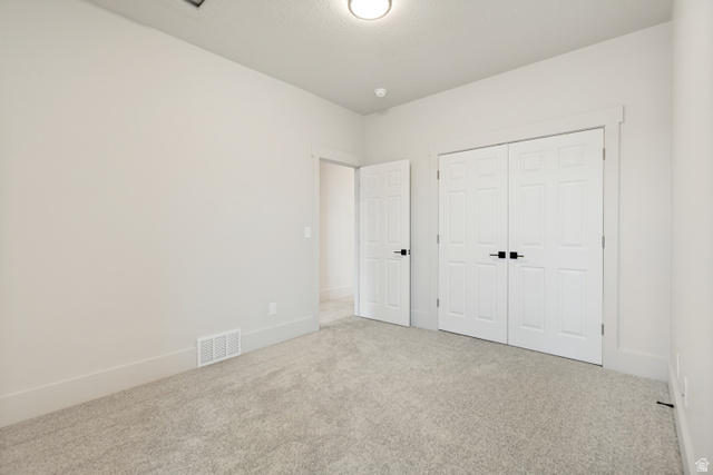 529 North Hvn Drive Mapleton, UT 84664 - Photo 24 of 30 Carpeted room featuring a double-door closet with black hardware, a single panel door, white baseboards, and neutral wall paint