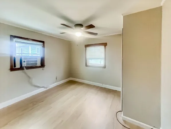 a view of empty room with wooden floor and fan