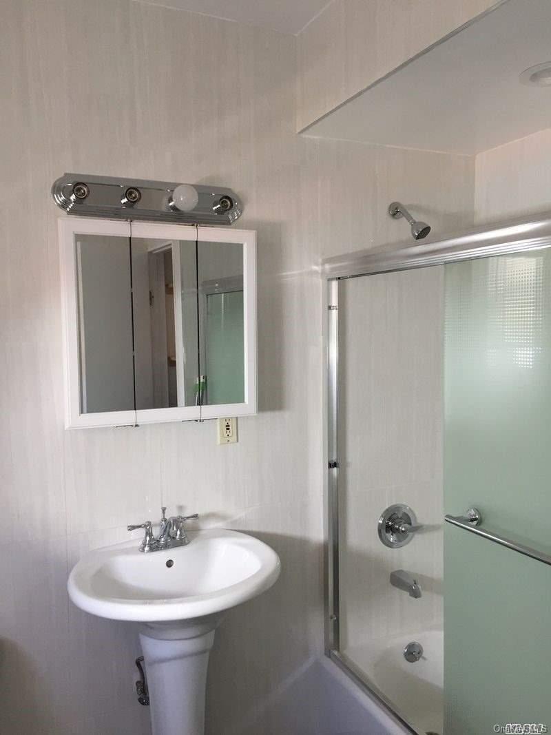 52-05 35th Street, Unit 2 Queens, NY 11101 - Photo 18 of 20 a bathroom with a sink a mirror and shower