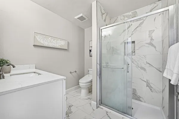 a bathroom with a granite countertop sink toilet and shower