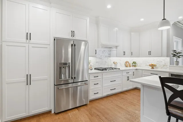a kitchen with stainless steel appliances kitchen island granite countertop a table chairs and white cabinets