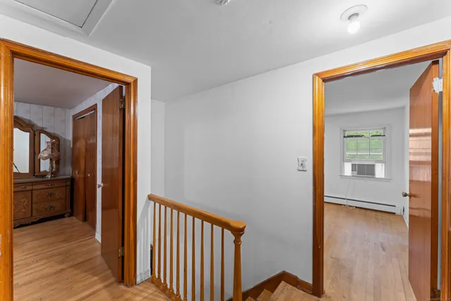 a view of a hallway with wooden floor and a kitchen
