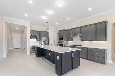 a large kitchen with stainless steel appliances a sink stove and cabinets