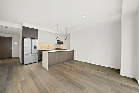 a large white kitchen with stainless steel appliances granite countertop a stove a sink and white cabinets with wooden floor