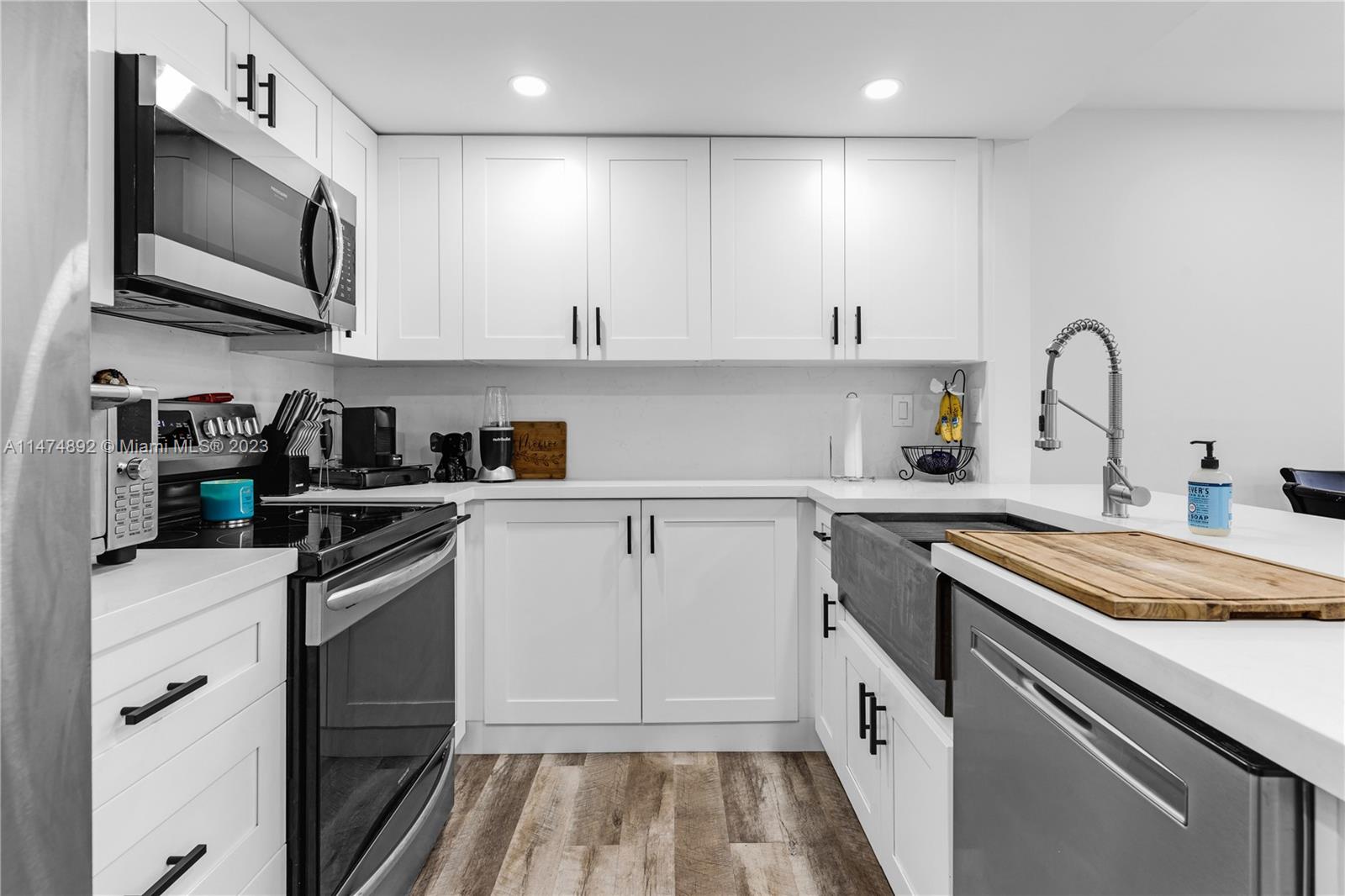 6825 Southwest 45th Lane, Unit 1 Miami, FL 33155 - Photo 11 of 28 a kitchen with stainless steel appliances granite countertop a sink and dishwasher a stove top oven with wooden floor