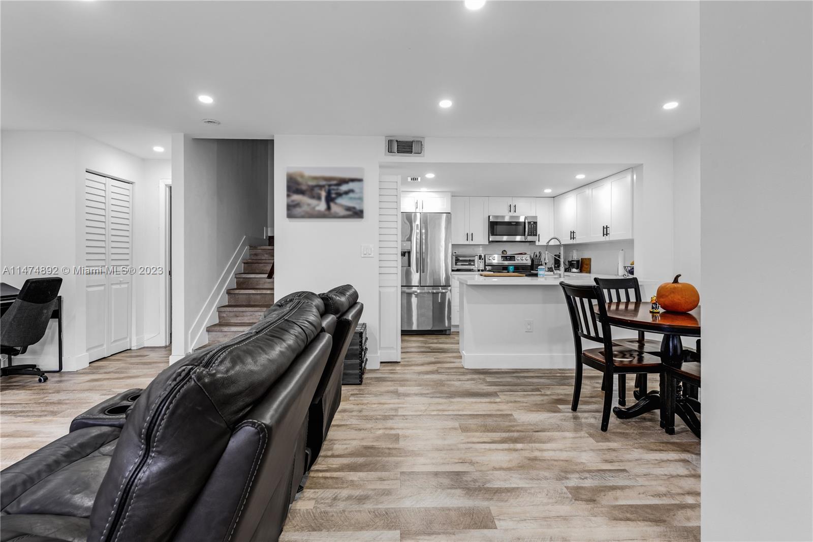6825 Southwest 45th Lane, Unit 1 Miami, FL 33155 - Photo 4 of 28 a kitchen with stainless steel appliances granite countertop a stove top oven a sink a dining table and chairs with wooden floor