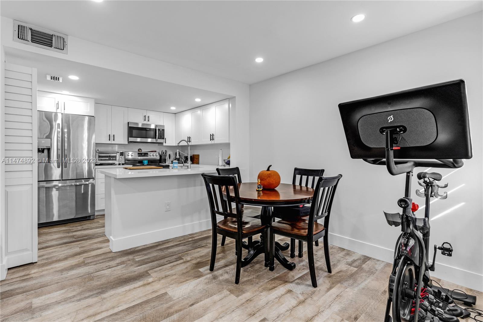 6825 Southwest 45th Lane, Unit 1 Miami, FL 33155 - Photo 7 of 28 a kitchen with a table chairs refrigerator and microwave