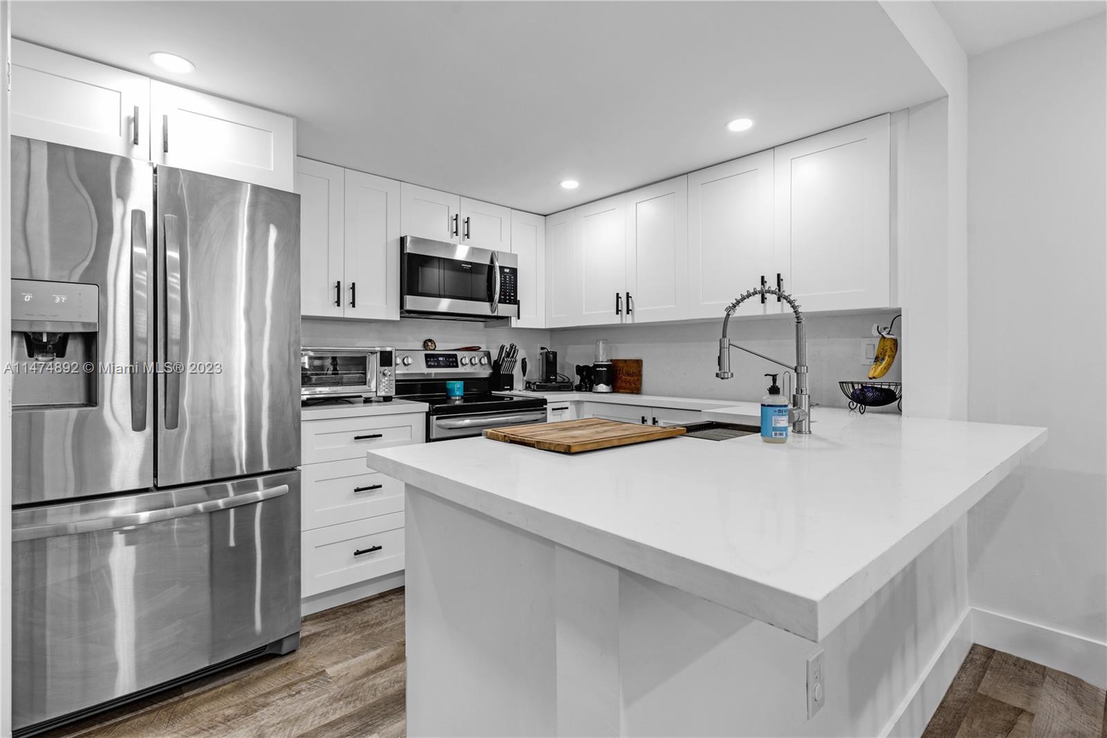 6825 Southwest 45th Lane, Unit 1 Miami, FL 33155 - Photo 10 of 28 a kitchen with kitchen island a white counter top space stainless steel appliances and cabinets
