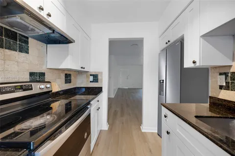 a kitchen with granite countertop a sink a stove and cabinets
