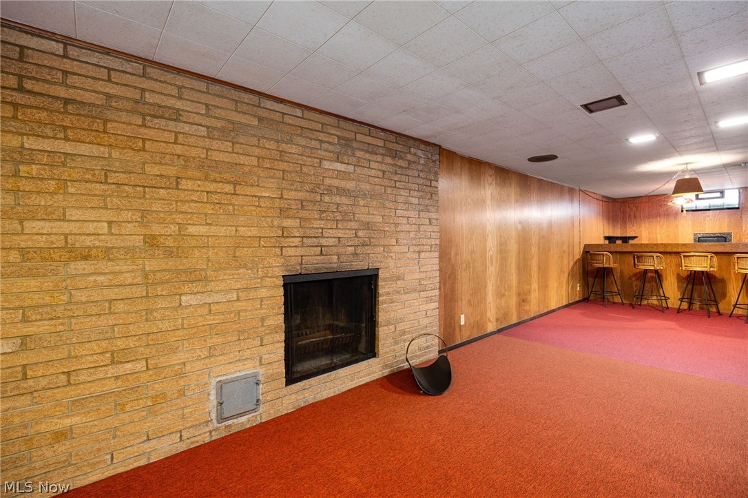 364 Mowbray Road Akron, OH 44333 - Photo 34 of 44 Basement with carpet flooring, a bar, a fireplace, and wood walls