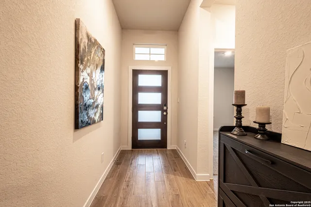 a view of a hallway with wooden floor and a bathroom