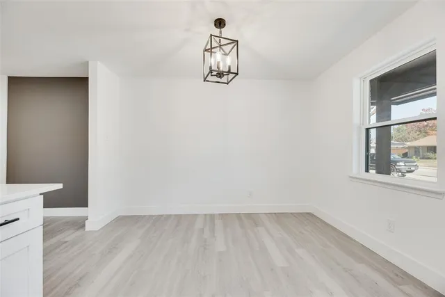 a large white kitchen with kitchen island a stove a sink a refrigerator and white cabinets with wooden floor