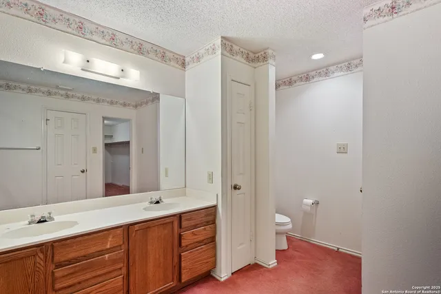 a spacious bathroom with a double vanity sink toilet mirror and shower