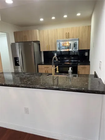 a kitchen with stainless steel appliances granite countertop a sink a refrigerator and a granite counter tops