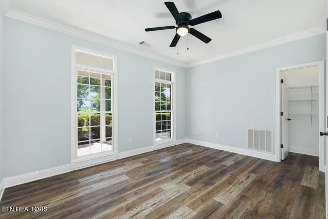 a view of an empty room with window and wooden floor