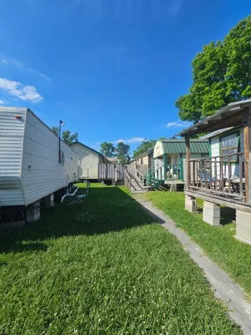 a view of house in front of a big yard with potted plants