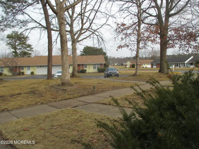 a view of a yard with a house and trees in the background