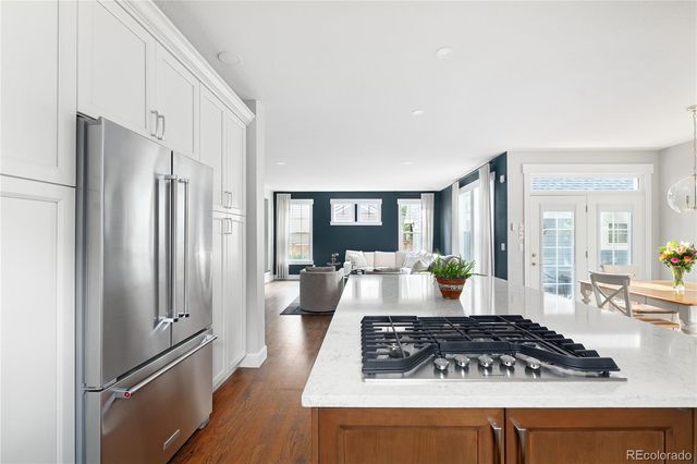 a living room with stainless steel appliances granite countertop a refrigerator stove and table
