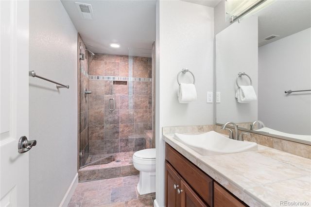a bathroom with a granite countertop sink a toilet and shower