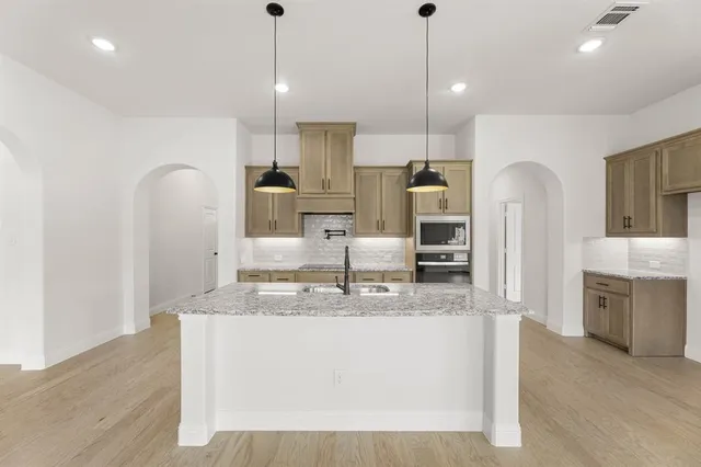 a kitchen with kitchen island a counter top space a sink stainless steel appliances and cabinets