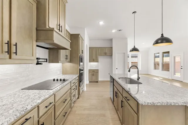a kitchen with stainless steel appliances granite countertop a sink a stove and a wooden floor