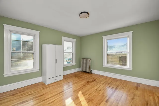 a view of an empty room with a window and wooden floor