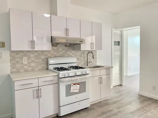 a kitchen with cabinets appliances and wooden floor