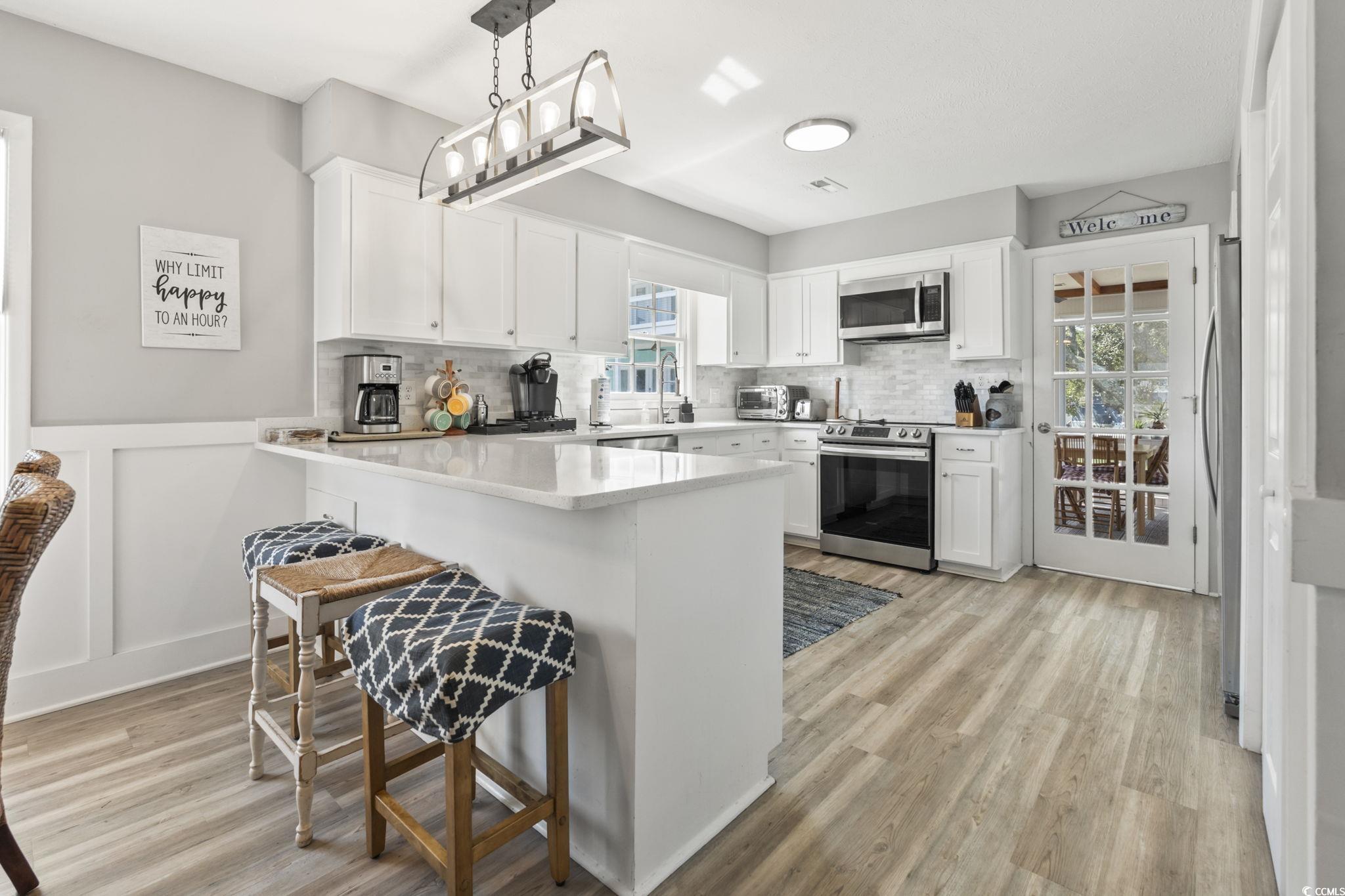 3182 State Rd S-26-816 Murrells Inlet, SC 29576 - Photo 3 of 40 Kitchen with a peninsula, stainless steel appliances, a breakfast bar area, white cabinets, and wainscoting