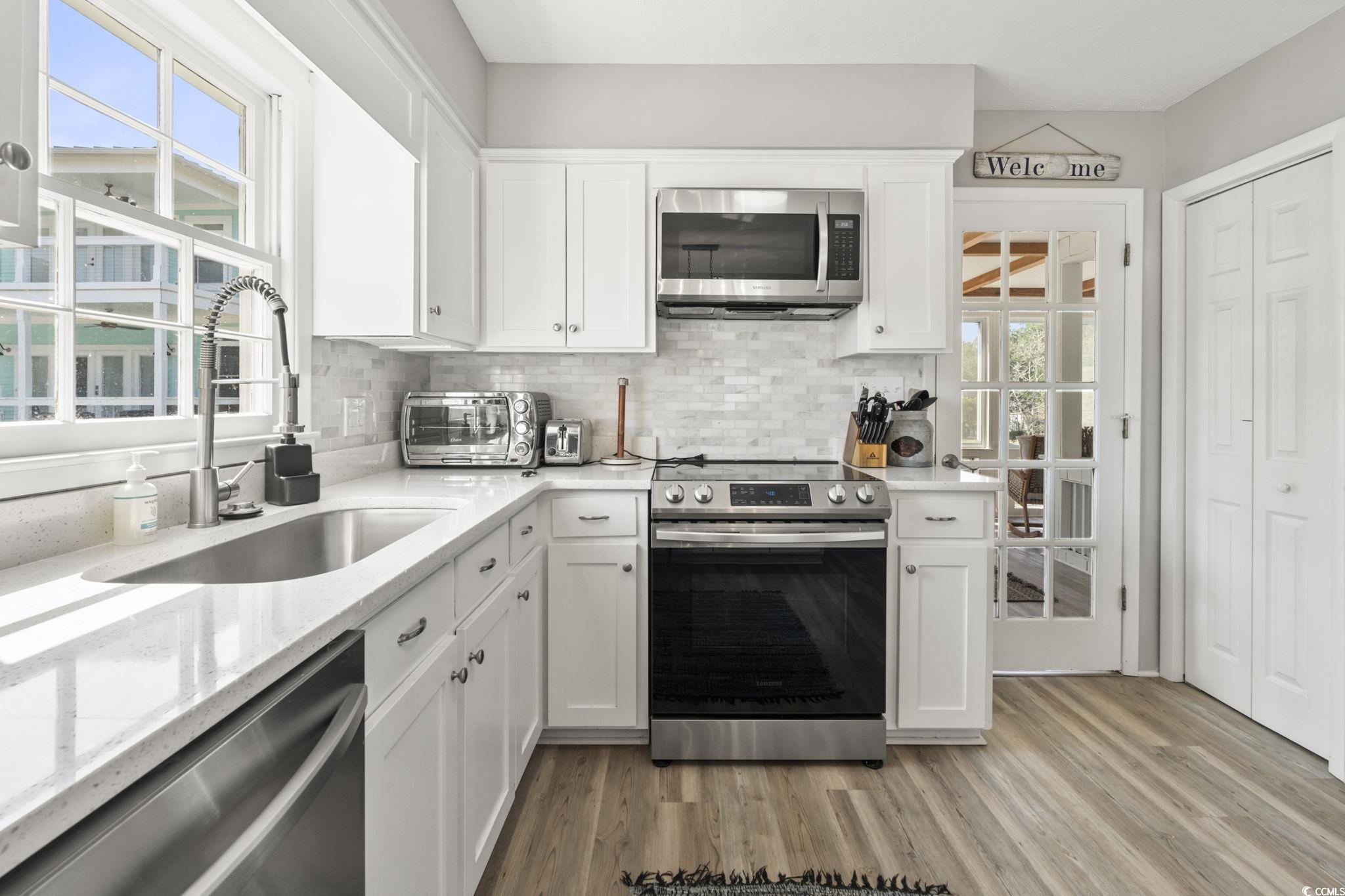 3182 State Rd S-26-816 Murrells Inlet, SC 29576 - Photo 4 of 40 Kitchen featuring stainless steel appliances, tasteful backsplash, white cabinetry, light wood finished floors, and light stone counters