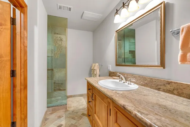 a spacious bathroom with a granite countertop sink mirror and a bathtub