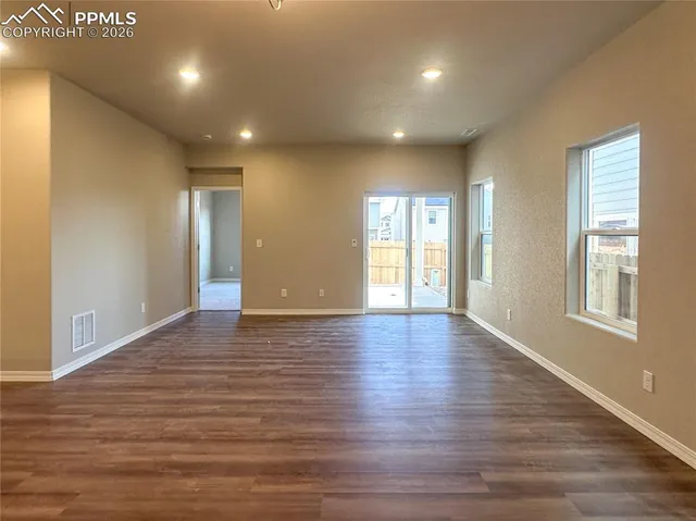 a view of an empty room with wooden floor and windows