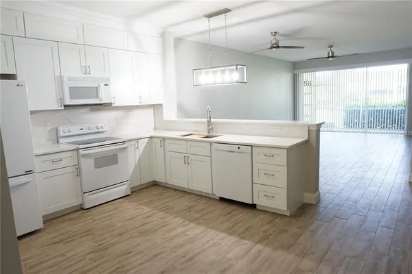 a kitchen with a sink white cabinets and white appliances