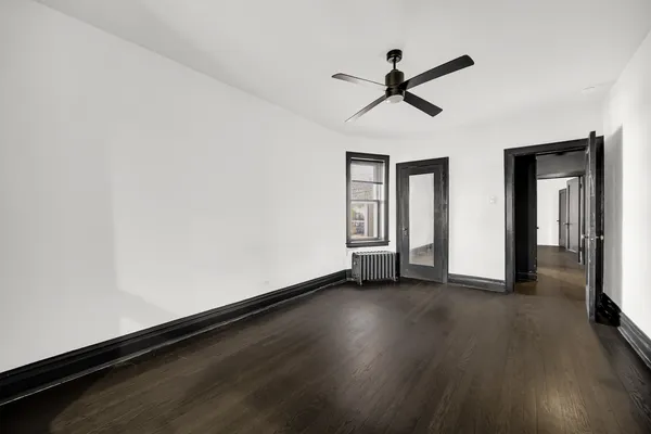 a view of empty room with wooden floor and fan