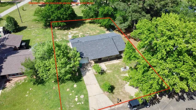an aerial view of a house with a yard and large trees