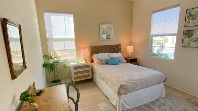 a bedroom with a bed table flowerpot and window