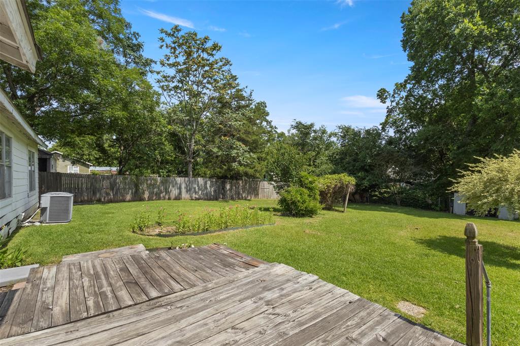 829 West 9th Street Bonham, TX 75418 - Photo 27 of 30 Expansive backyard featuring a natural wood deck, established privacy fencing, a manicured lawn, and mature trees