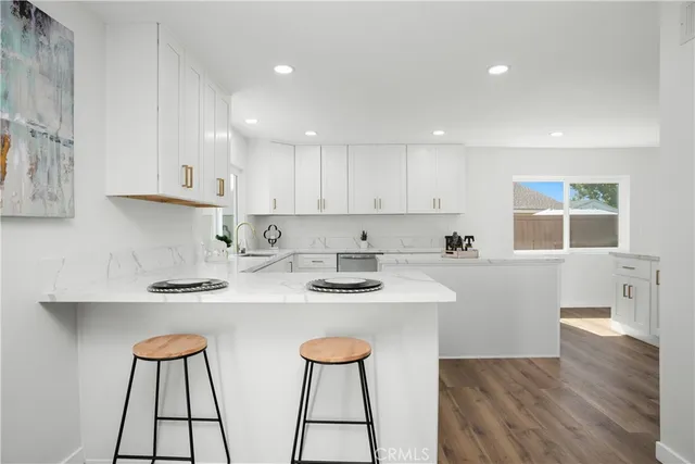 a kitchen with stainless steel appliances a stove a sink and white cabinets with wooden floor