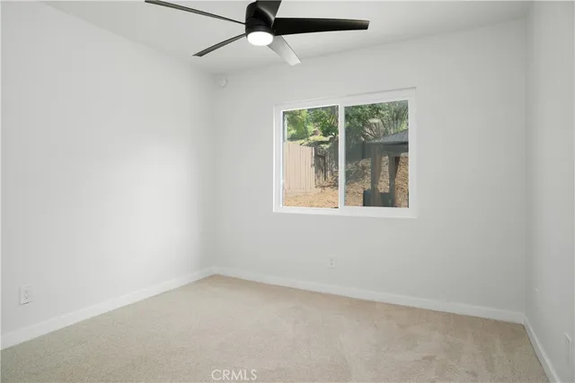 an empty room with a window and a ceiling fan