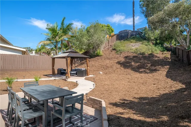a view of a backyard with table and chairs plants and wooden fence