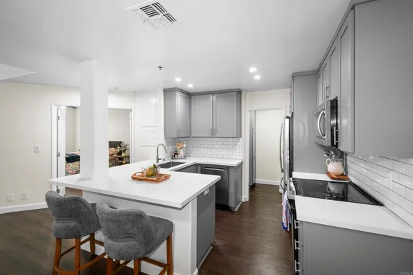 a kitchen with a refrigerator a stove and a dining table with wooden floor