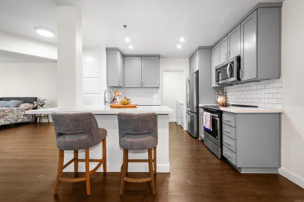 a kitchen with stainless steel appliances granite countertop a stove top oven a sink dishwasher a dining table and chairs with wooden floor