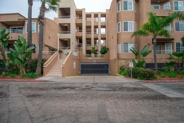 a front view of a multi story residential apartment building with yard and parking