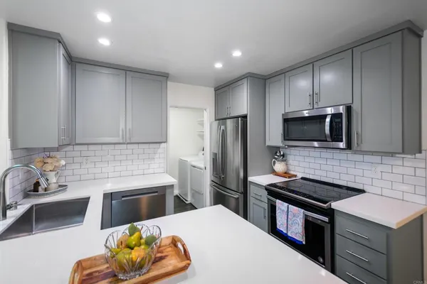 a kitchen that has a sink cabinets and stainless steel appliances