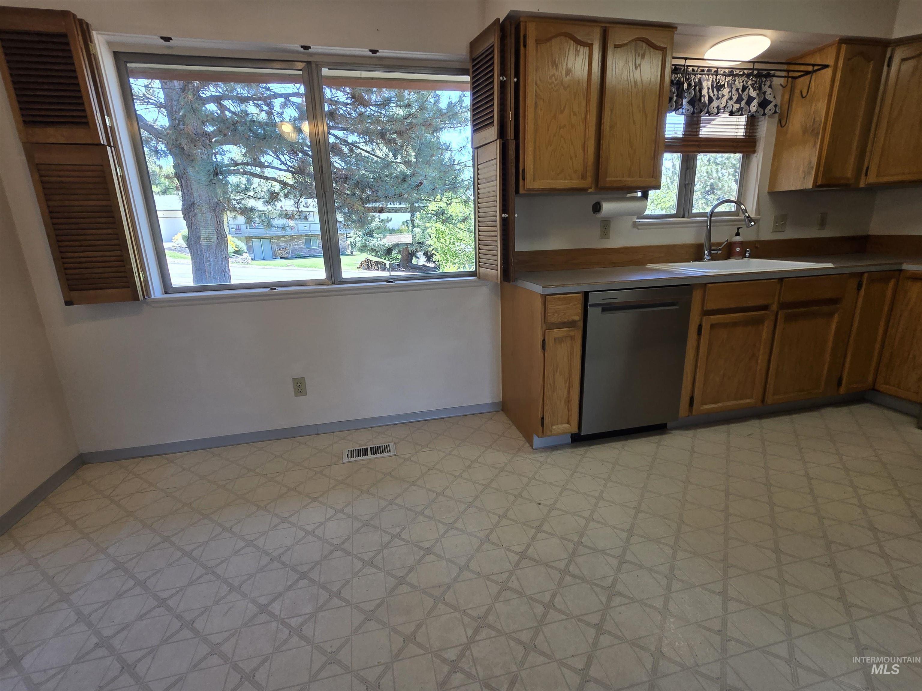 12050 West Hidden Valley Rim Road Boise, ID 83709 - Photo 4 of 39 Kitchen featuring wood-finish cabinetry, stainless steel dishwasher, and a window with a sink