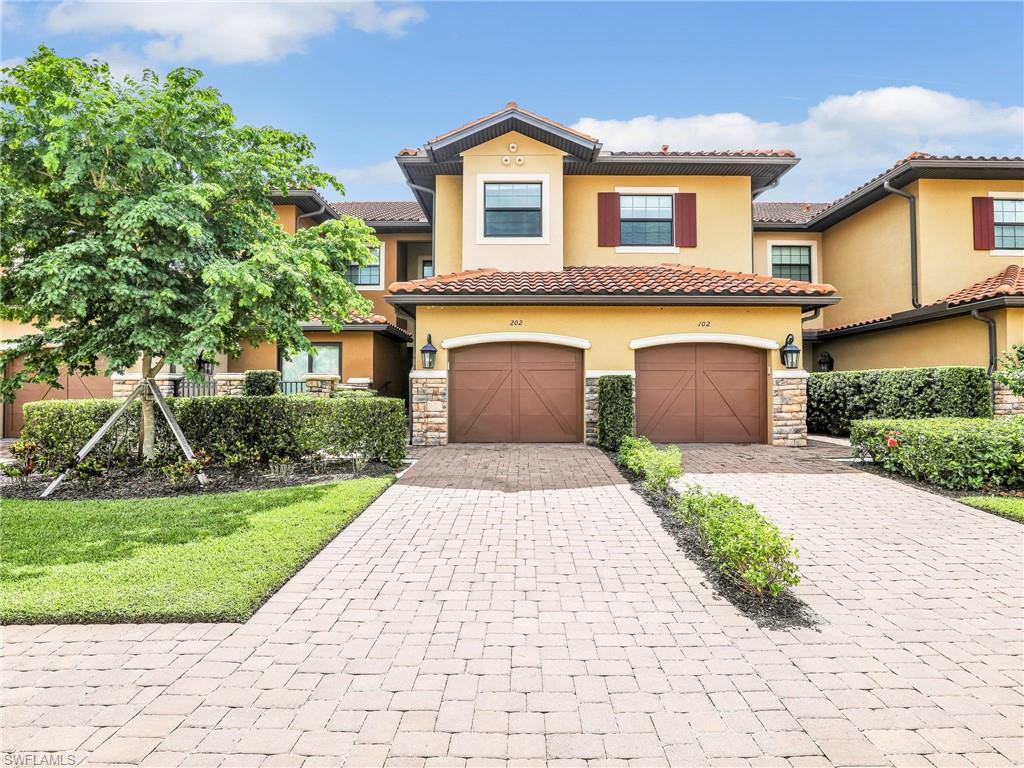 9685 Montelanico Loop, Unit 202 Naples, FL 34119 - Photo 3 of 41 a front view of a house with a garden and trees