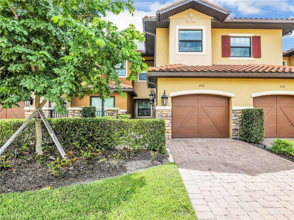 9685 Montelanico Loop, Unit 202 Naples, FL 34119 - Photo 4 of 41 a front view of a house with a yard and garage