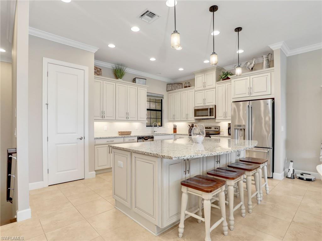 9685 Montelanico Loop, Unit 202 Naples, FL 34119 - Photo 8 of 41 a large kitchen with kitchen island a sink and a refrigerator